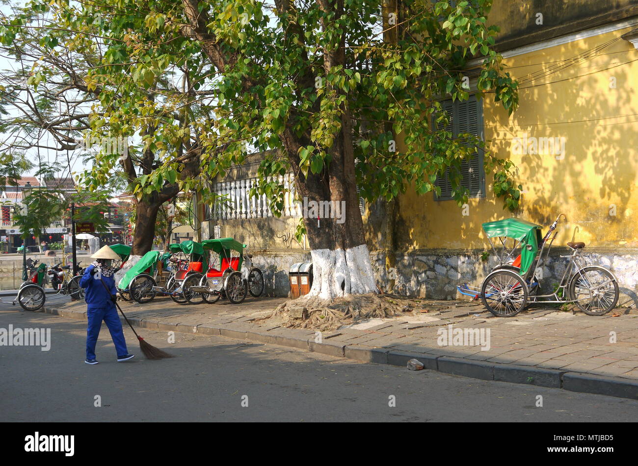HOI AN, VIETNAM - 20. MÄRZ 2018: Kehrmaschine Arbeiter mit Besen Reinigung der Straße im Zentrum der Weltkulturerbe Stadt Hoi An Stockfoto