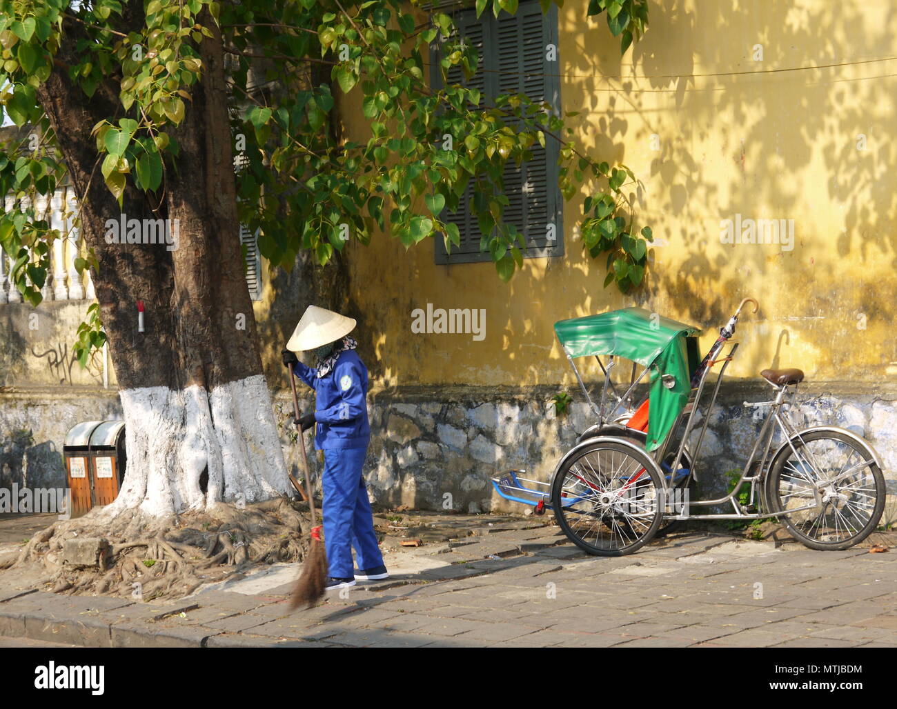 HOI AN, VIETNAM - 20. MÄRZ 2018: Kehrmaschine Arbeiter mit Besen Reinigung der Straße im Zentrum der Weltkulturerbe Stadt Hoi An Stockfoto