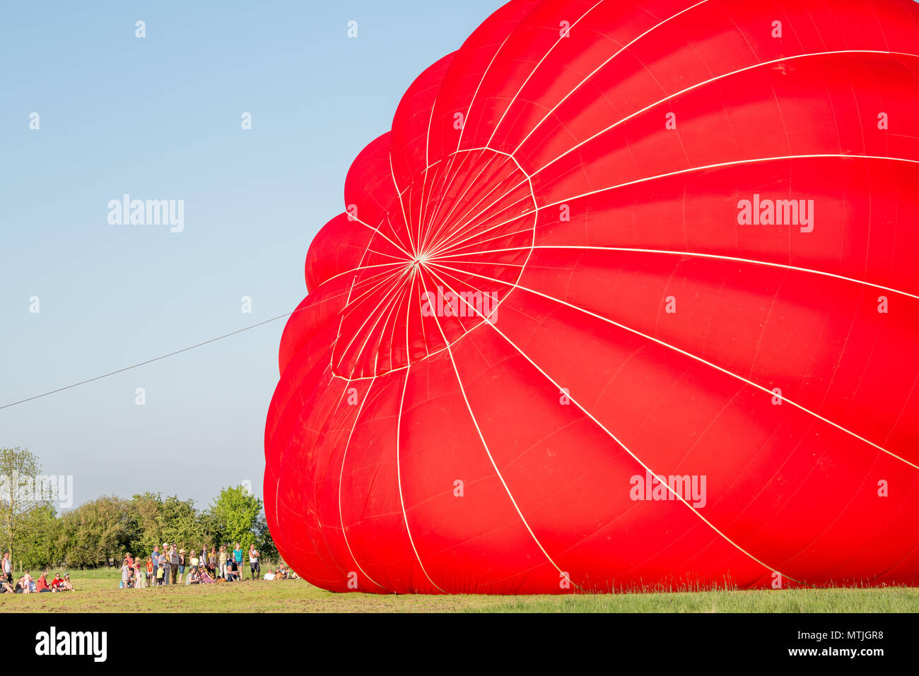 Zuschauer verfolgen als rote Jungfrau Hot Air Balloon bläst sich auf Lyndon Top, Rutland Water, England. Stockfoto