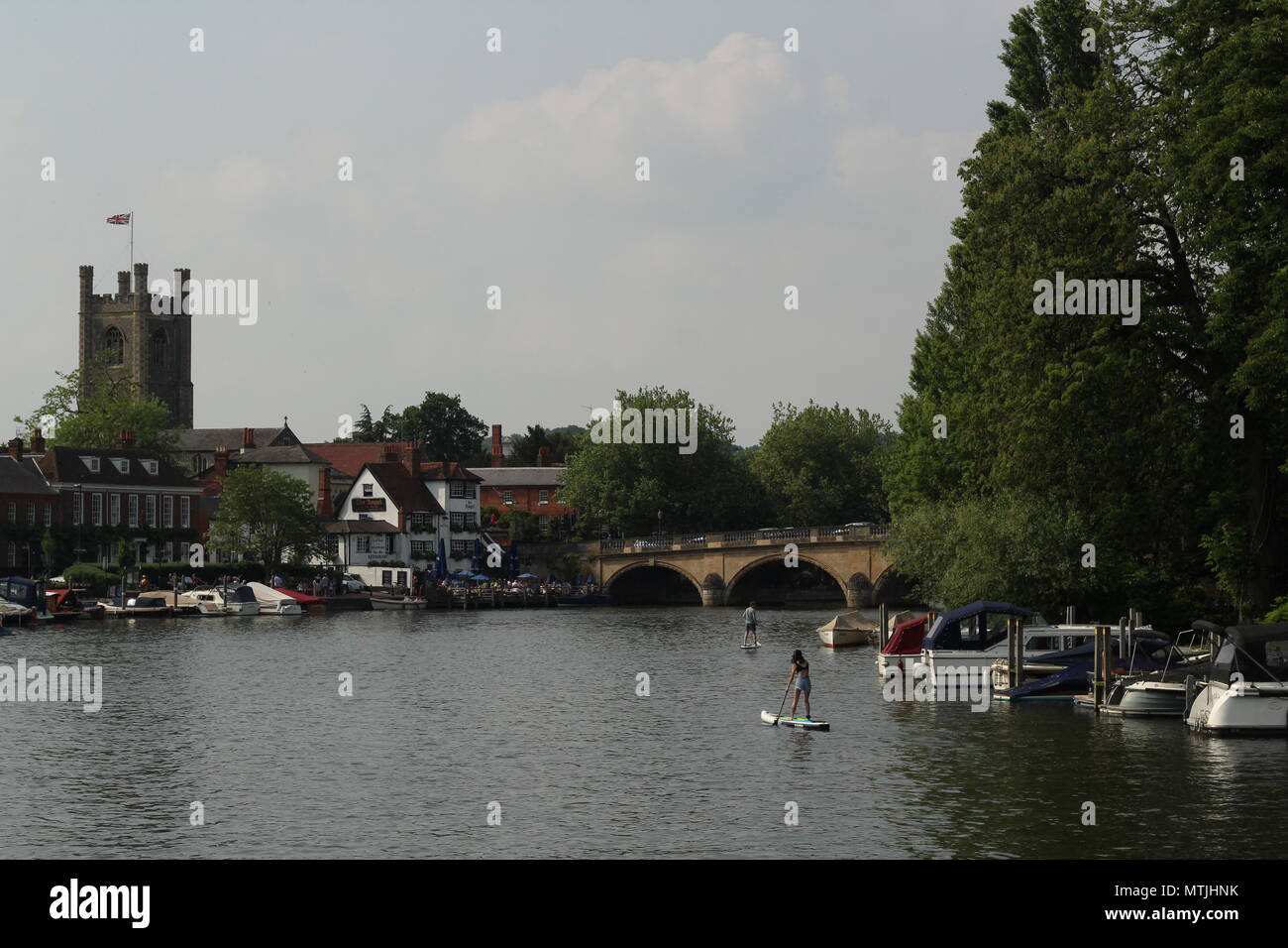 Zwei Personen paddlesurfing entlang der Wasserstraße in Richtung der Angel Inn und Brücke am Henley on Thames Oxfordshire. Stockfoto