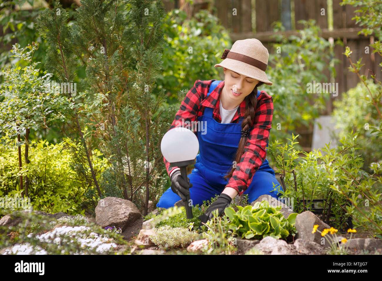 Junge Frau Landschaft Designer Installationen dekorative Lampe auf flower bed Stockfoto