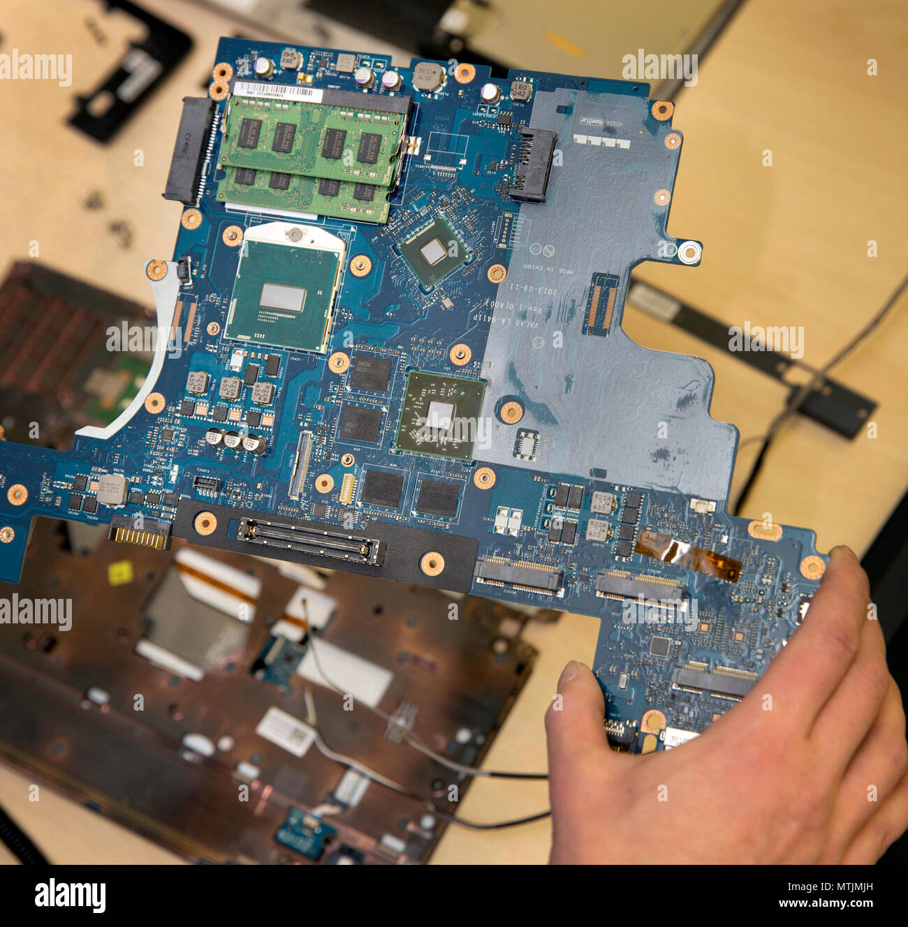 Ein Techniker mit einem Laptop Motherboard - auf dem Board montiert ist die CPU und 2 Sticks von Arbeitsspeicher (RAM). Stockfoto