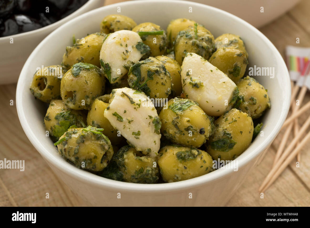 Schüssel mit grünen Oliven, Knoblauch und Koriander als Snack Nahaufnahme Stockfoto