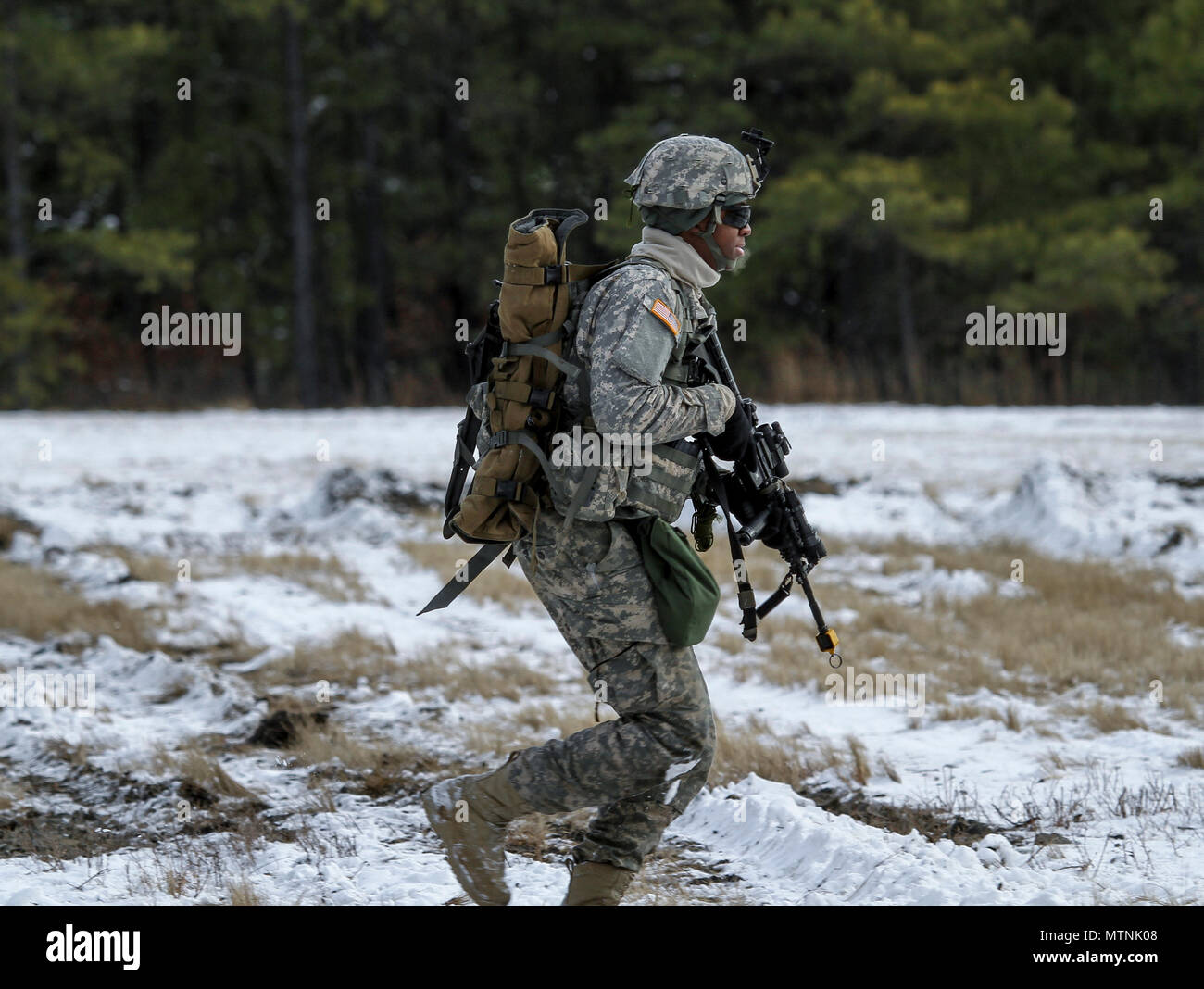 Ein New-jersey Army National Guard Soldat mit dem 1-114 th Infanterie läuft zum woodline nach eine Insertion von Marine Flugzeuge Gruppe 49 UH-1Y Huey Hubschrauber bei einer gemeinsamen Übung am Joint Base Mc Guire-Dix - Lakehurst, New Jersey, Jan. 10, 2017. Das Marine Corps Reserve Luftbrücke und Close Air Support zu Alpha Company Soldaten von 1-114. Die 1-114, die Teil der 50th Infantry Brigade Combat Team, beteiligt sich an einer Reihe von Schulungen, die in diesem Sommer wird an eine exportierbare Kampftraining Fähigkeit Übung auf Fort Pickett, Va. Die Armee der Nationalen Gua münden Stockfoto