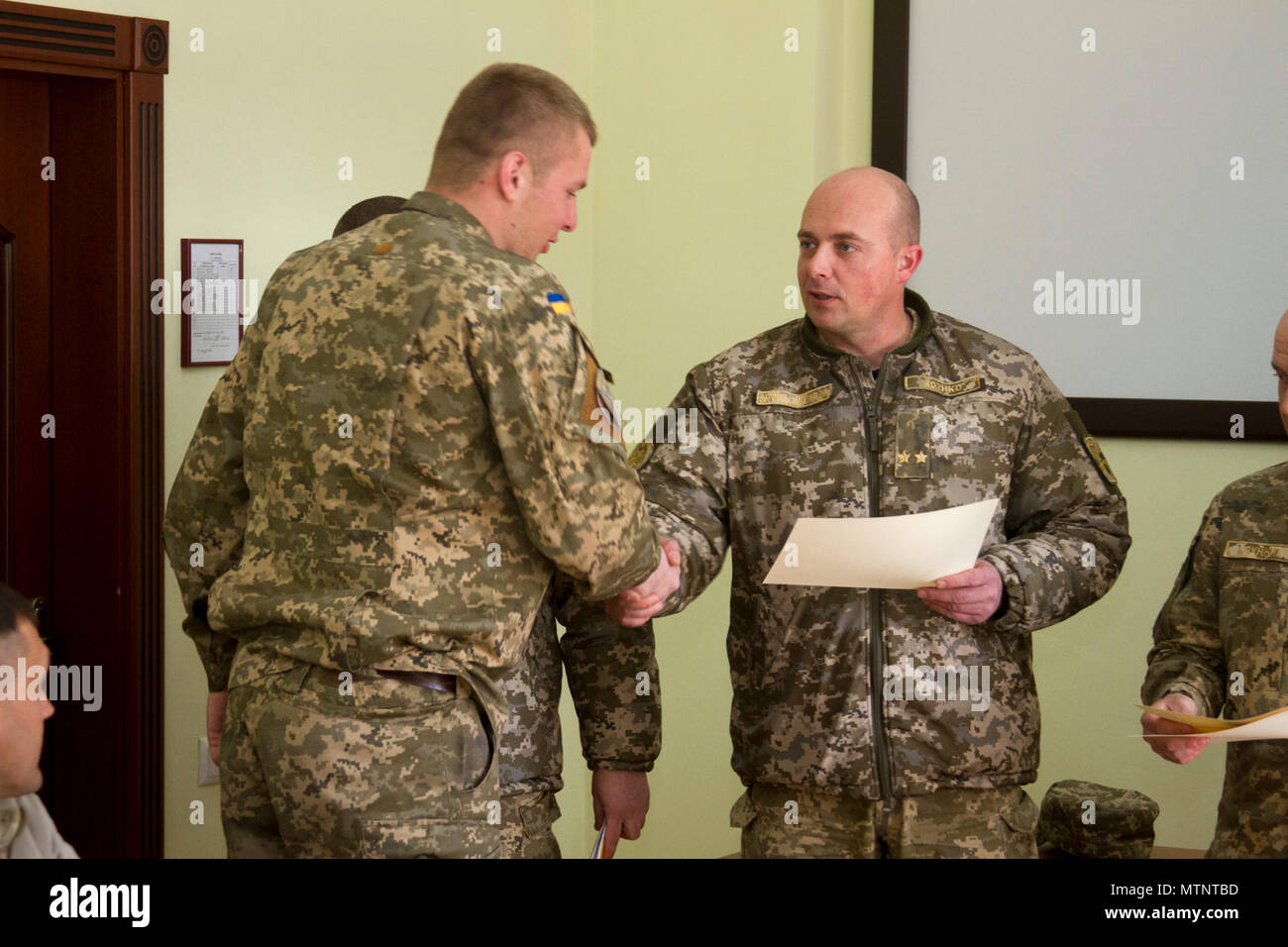 Ukrainische Oberstleutnant Pavlo Rozhko, der Kommandant der Yavoriv Combat Training Center, präsentiert ein Absolvent des CTC Beobachter Controller Trainer Akademie mit einem Zertifikat während einer Diplomverleihung an der CTC auf der internationalen Friedens und der Sicherheit, in der Nähe der Yavoriv, der Ukraine, der am 25. April. Stockfoto