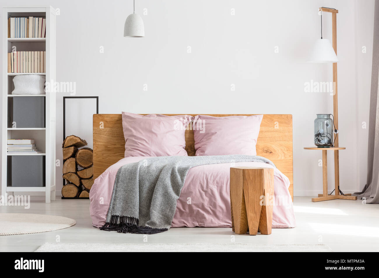 Holzdekor geräumiges Schlafzimmer mit rosa Bettwäsche und weißen Wänden Stockfoto