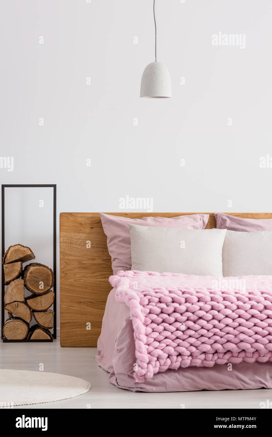 Holz liefert, die durch hölzerne Bett im gemütlichen weißen Schlafzimmer Stockfoto