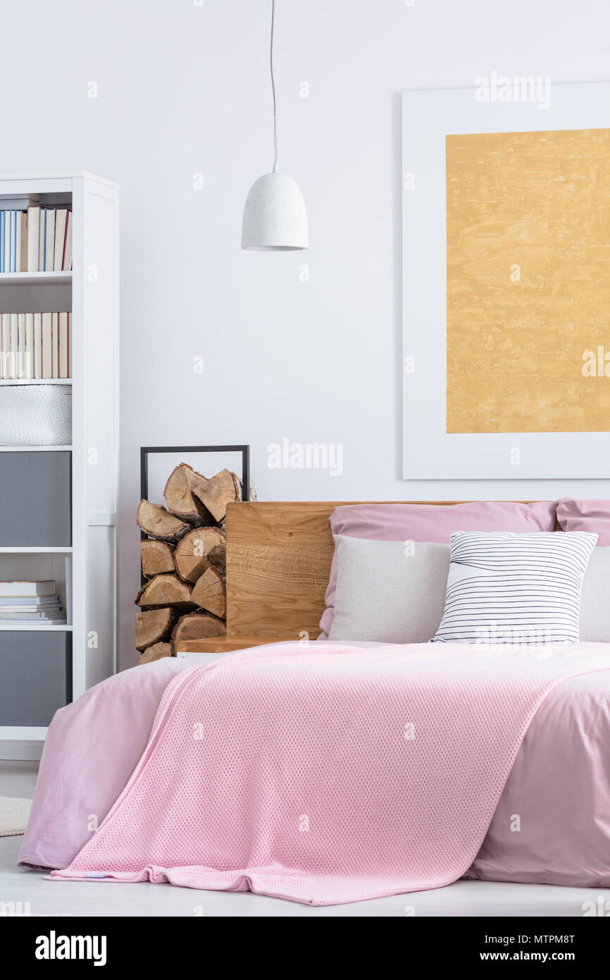 Einfache rosa Schlafzimmer mit gemütlichen großen Bett und Holz liefert Stockfoto