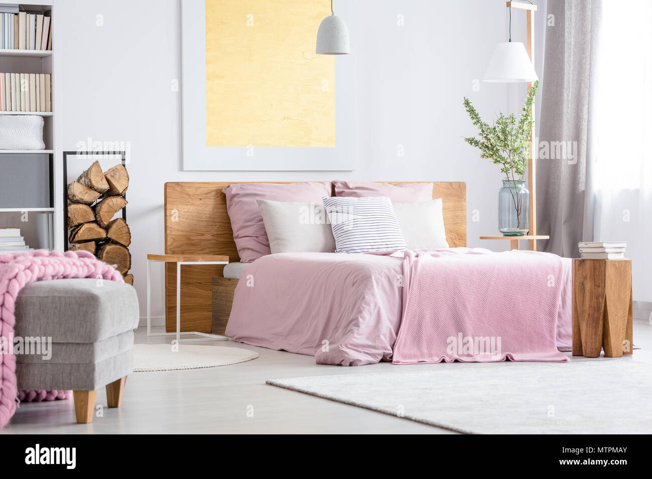 Großes Bett aus Holz mit rosa Bettwäsche in den gemütlichen weißen Schlafzimmer Stockfoto