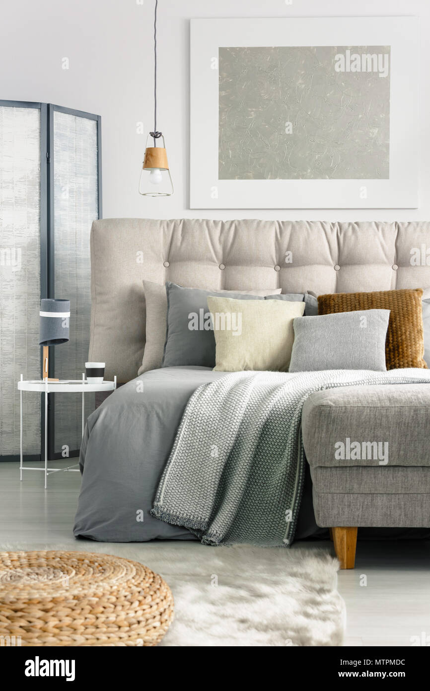 Graue Decke und Kissen auf dem bequemen Bett im geräumigen Schlafzimmer Stockfoto