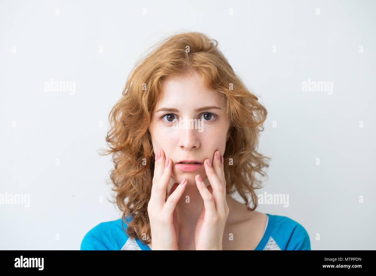 Erstaunt weibliche Modell mit roten lockigen Haar, trug ein T-Shirt, mit genervt die Augen Stockfoto