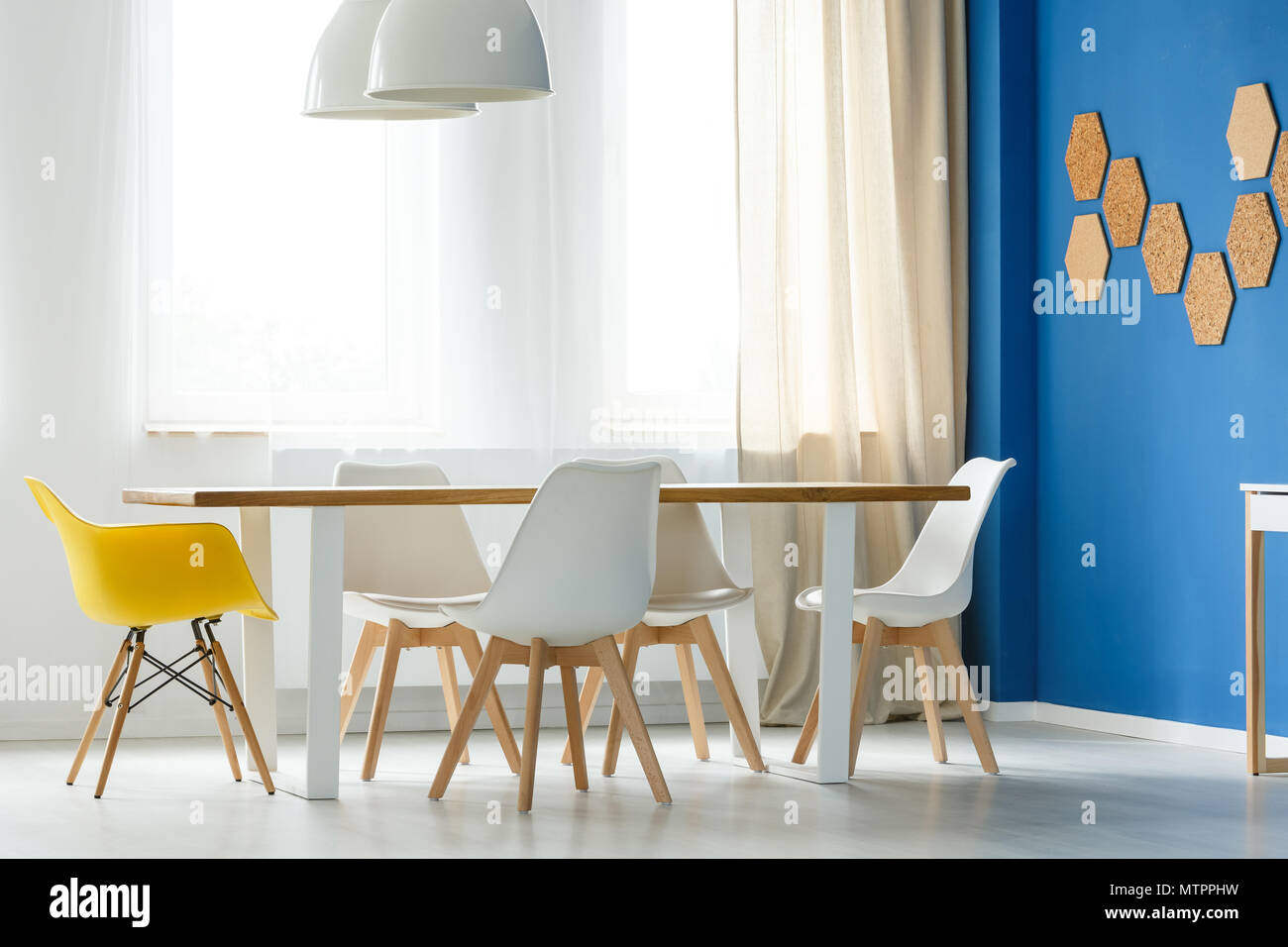Multifunktionale skandinavischen Home Interior mit Gemeinschaftstisch,  weiße und gelbe Stühle, blaue Wand, Lampen und Fenster mit Lichtvorhänge  Stockfotografie - Alamy