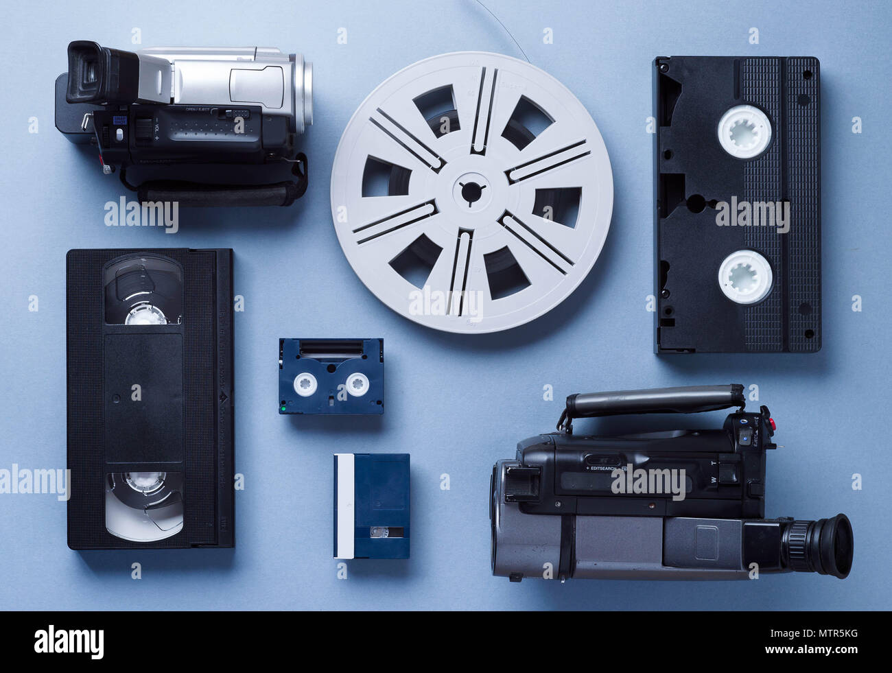 Videokameras, VHS und Mini Kassetten und einer Folienrolle gut über blauen Hintergrund angeordnet, vor anzeigen Stockfoto