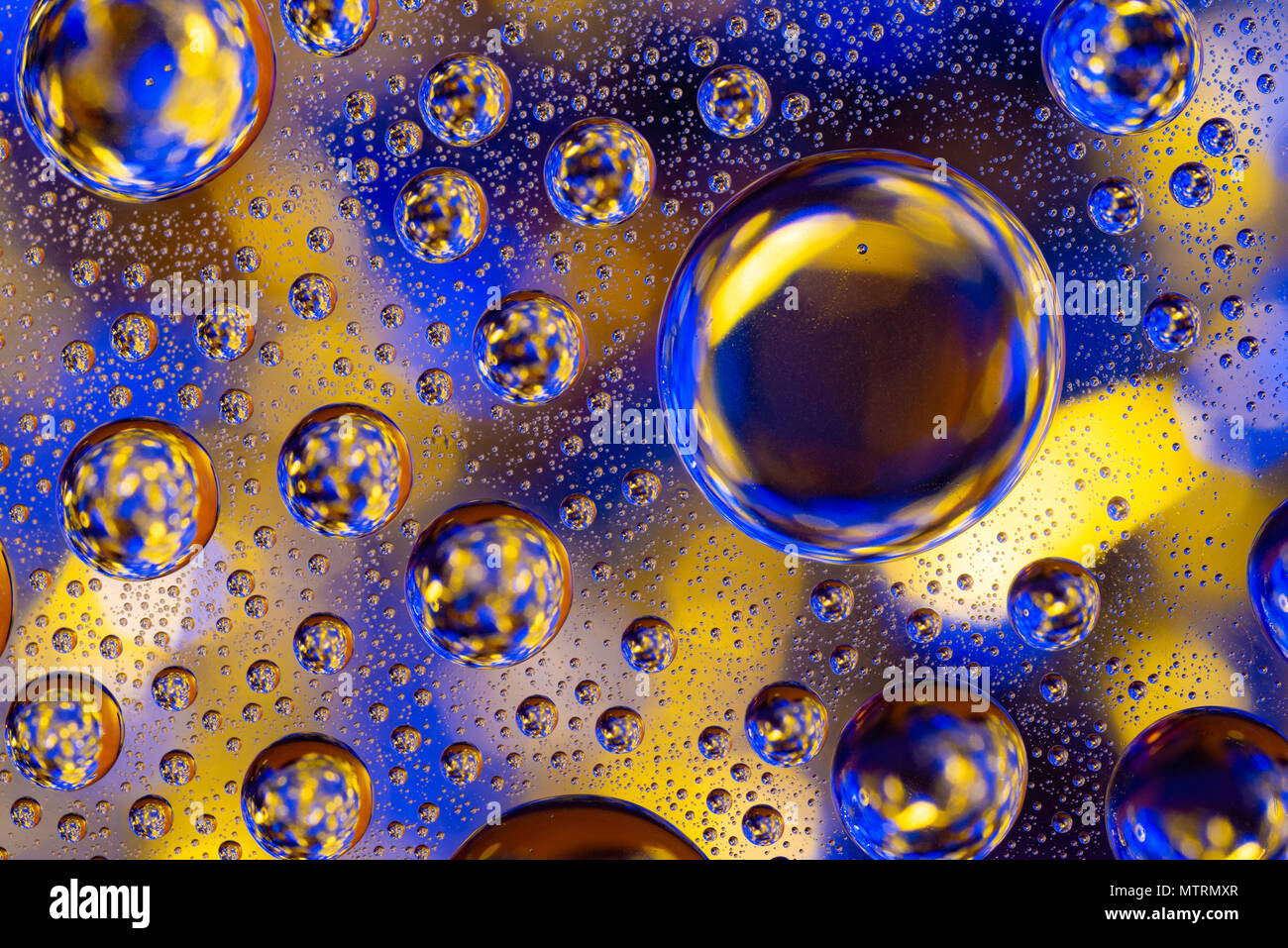 Wassertropfen auf Glas mit Gelb und Gold beleuchteten Hintergrund Stockfoto