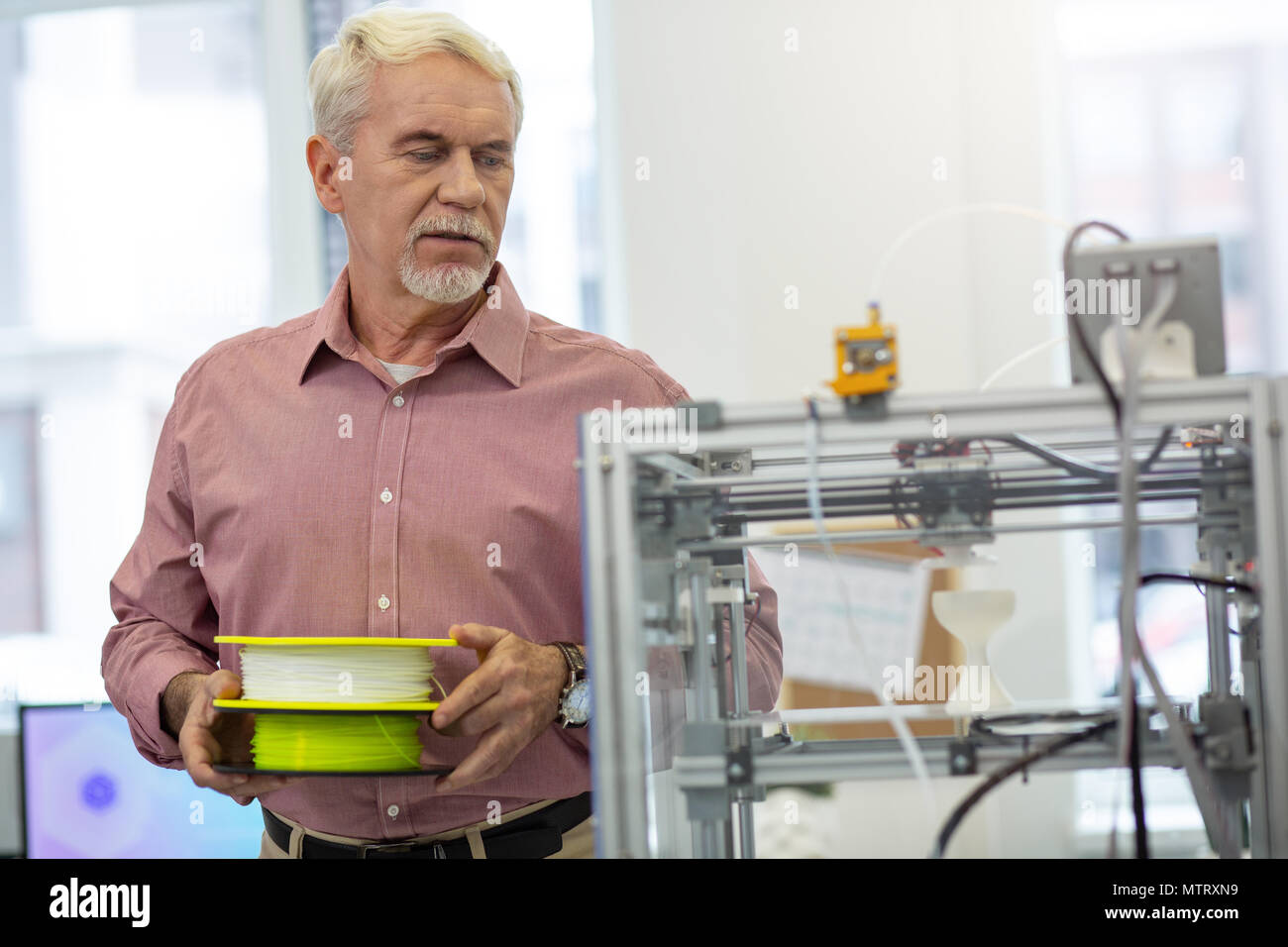 Gut aussehender älterer Menschen, der sich über die glühwendel Drucker ändern Stockfoto