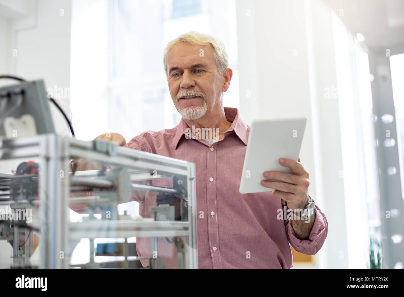 Senior im Büro Ändern der Einstellungen von 3D-Drucker Stockfoto