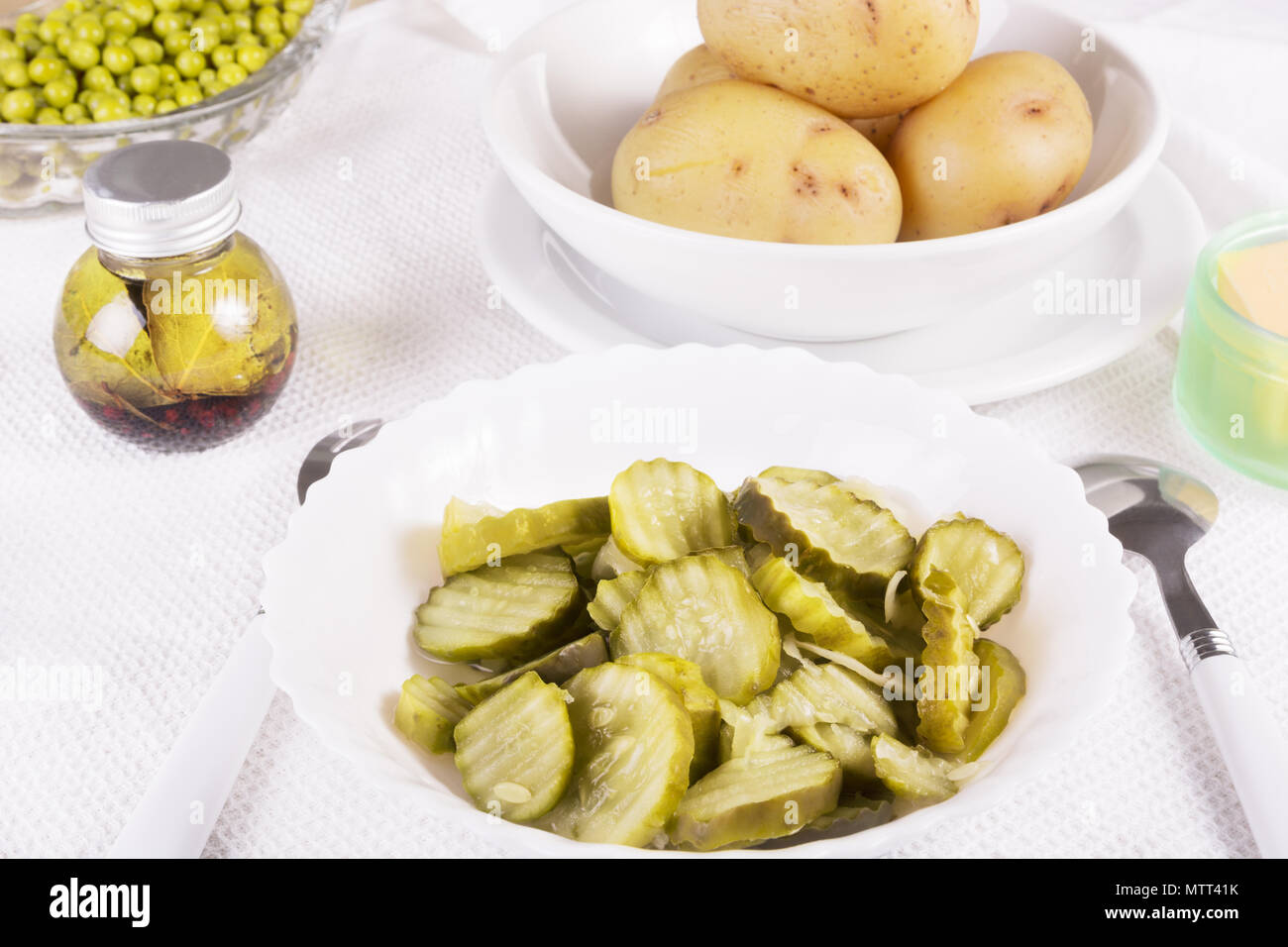 Gesunde, einfaches Essen - geschnittene Gurke Gurken in einer weißen Schüssel, gekochte Kartoffeln, grüne Erbsen, Öl und Butter Stockfoto