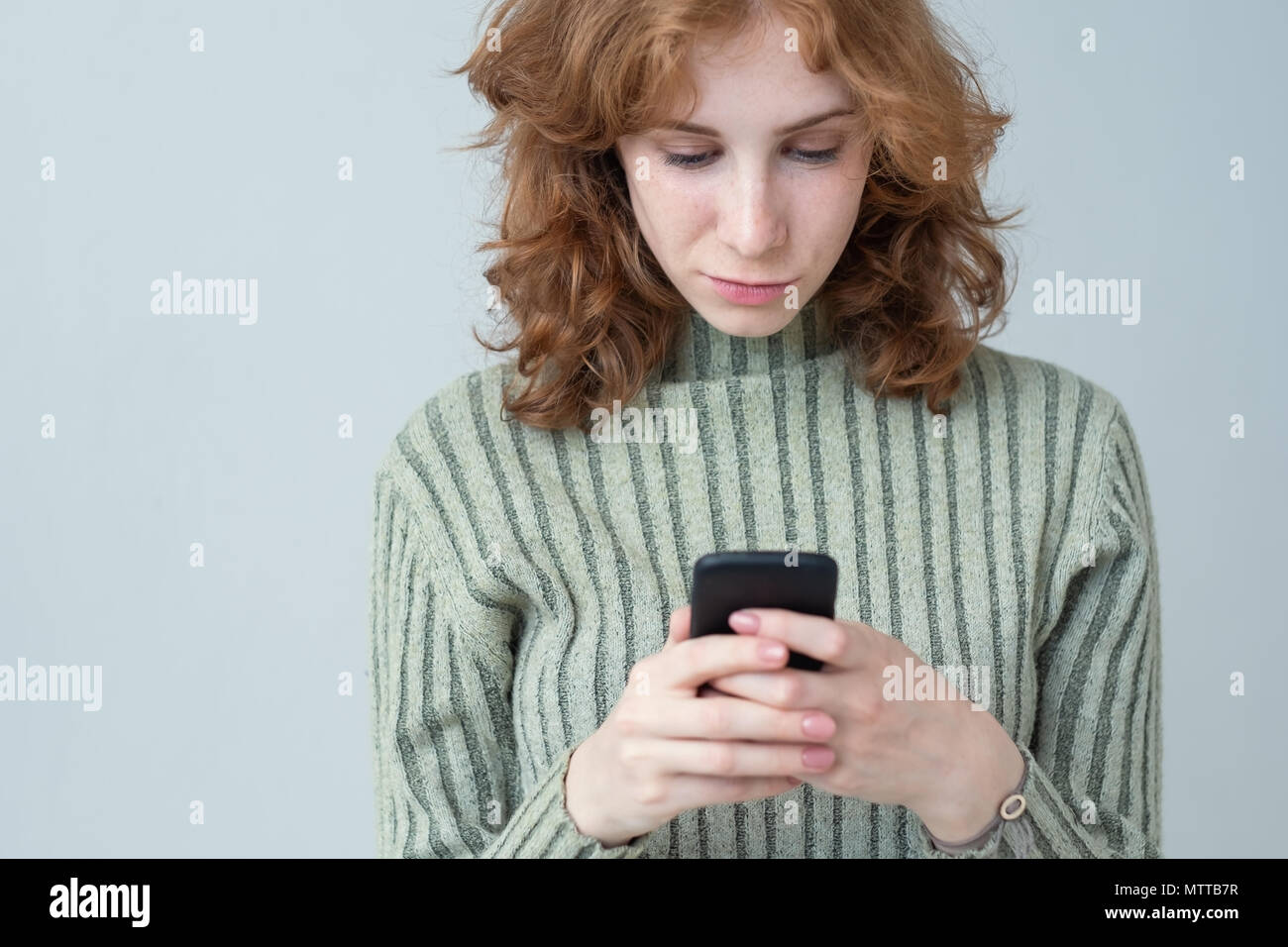 Ziemlich kaukasische Mädchen mit roten Haaren Senden von SMS Stockfoto