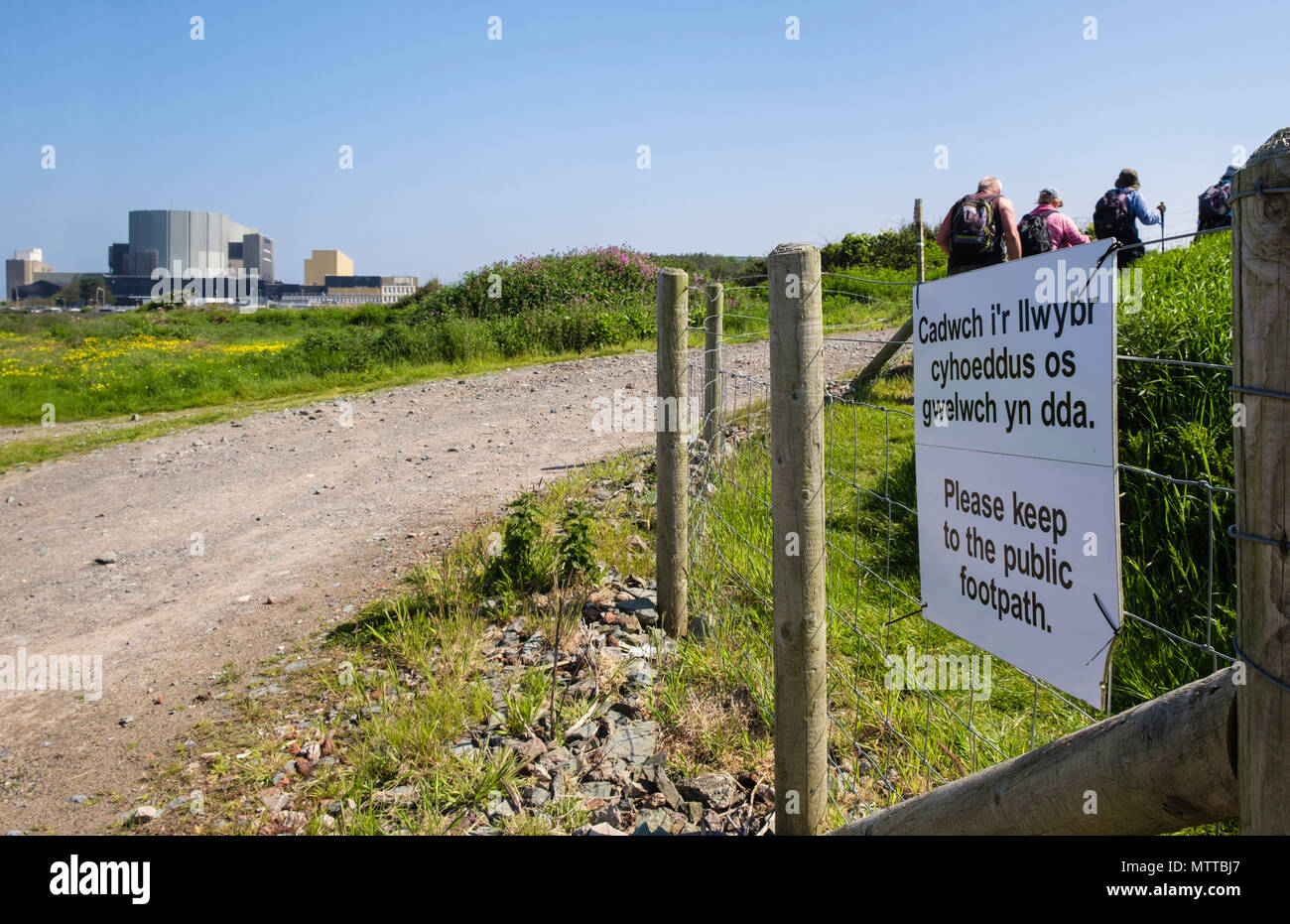 Zweisprachiges Schild auf Anglesey Coastal Path wieder um Wylfa Kernkraftwerk mit Wanderer Wandern im Jahr 2018 geleitet. Cemaes ISLE OF ANGLESEY Wales UK Stockfoto