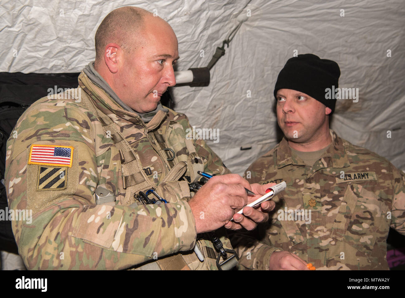 Grafenwöhr, Deutschland - Sgt. Tschad F. Salinero, ein Flug medic mit C Company, 1-214 th Allgemeine Luftfahrt, erhält Bericht über einen simulierten Unfall von Maj. Joshua A. Scott, eine allgemeine Chirurg mit 67 Vorwärts OP-Team, vor aeromedical Evacuation, Jan. 11, 2017. (U.S. Armee Foto von Maj. Chris N. Angeles, 67 Vorwärts Op-Team) Stockfoto