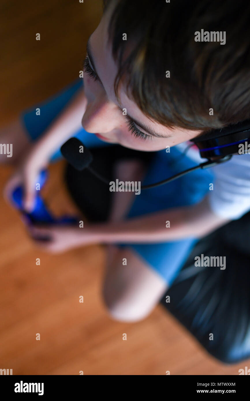 Ein Teenager mit einem Headset und Mikrofon, während die Playstation PS4 online zu kommunizieren, seine Teamkollegen im Spiel Fortnite. Stockfoto