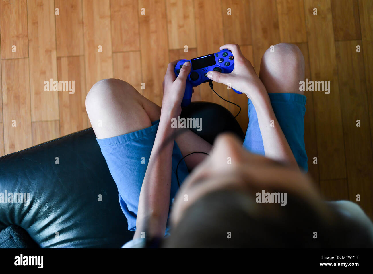 Ein Teenager mit einem Headset und Mikrofon, während die Playstation PS4 online zu kommunizieren, seine Teamkollegen im Spiel Fortnite. Stockfoto