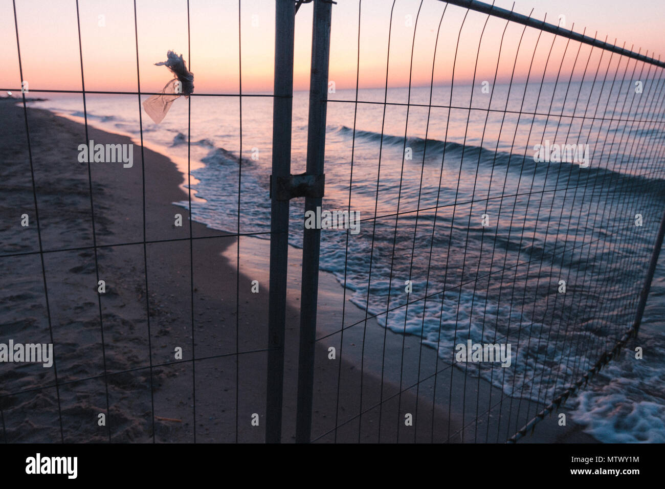 Sunsut am Strand an der See oder das Meer hinter dem gitterzaun Stockfoto