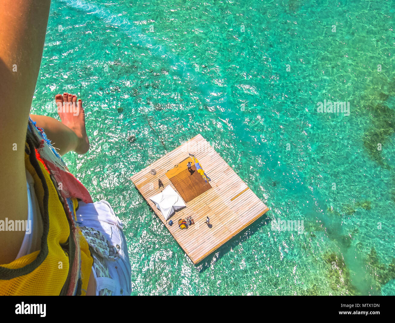Antenne Detailansicht einer Frau Parasailing. Unten, die Landeplattform auf die spektakuläre Blaue Meer von Deer Island, Ostküste von Mauritius, Indischer Ozean. Stockfoto