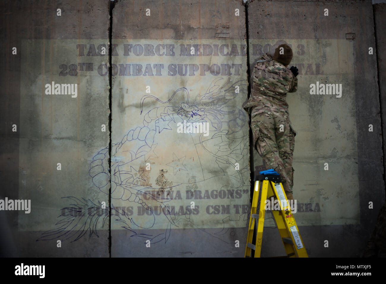 Us-Armee Sgt. 1. Klasse Mirna Velez, 28 Combat Support Hospital Op noncommissioned Officer, Spuren der Umriss der Task Force Medical Rolle 3 Logo, auf eine konkrete Wand außerhalb der 28 CSH, in der Nähe von Bagdad, Irak, Jan 4, 2017 projiziert. Der 28 CSH ist die Vorbereitung auf eine Umschichtung, die Übergabe der Verantwortung an die 21 CSH von Fort Hood, Texas, nachdem Sie den Befehl mission medizinische Befähiger und dient als Medical Hub für Combined Joint Task Force - inhärenten Lösen zu stabilisieren, Halten und Bühne kritisch Kranken und Verletzten Opfer während Luft warten auf e Stockfoto