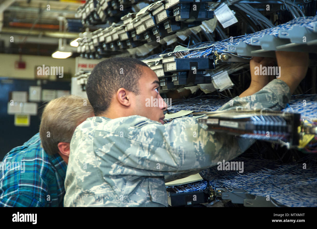 Airman 1st Class Nicklaus Norman, voice Netzwerk system Techniker, und Doug Vonada, 88th Communications Squadron Telefon Werkstatt Leiter der Voice network System, Trace eine der tausenden von Telefonleitungen, die durch den Hauptverteiler für Bereich A auf Wright-Patterson Air Force Base, Ohio, Jan. 27, 2017. Die 88 CS betreibt zwei Werkstätten und Verteiler - eine für jeden Bereich der Base - jedes mit Tausenden von Telefonleitungen auf der Durchreise. (U.S. Air Force Foto von R.J. Oriez/Freigegeben) Stockfoto