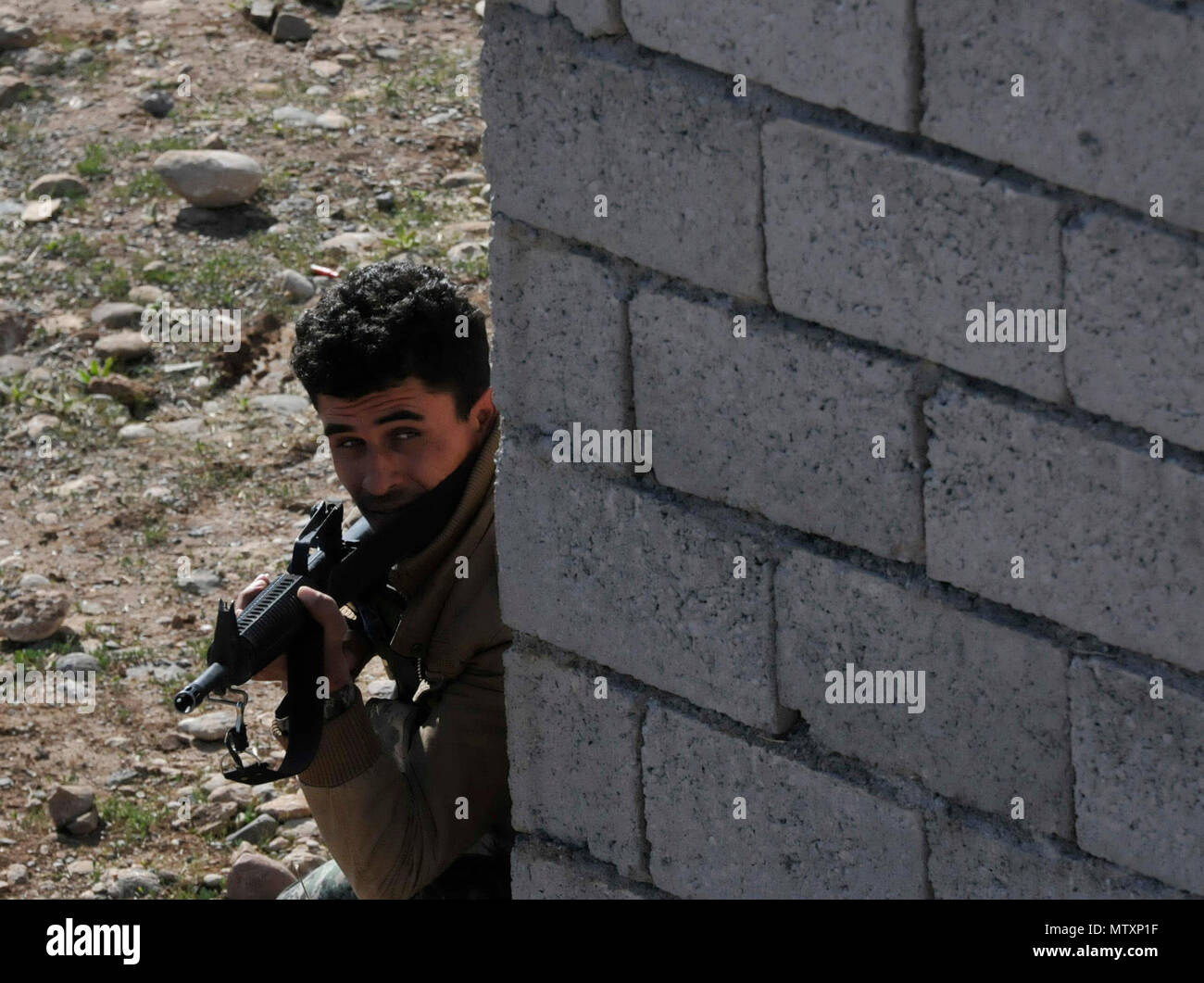 Ein peshmerga Soldat blickt vorsichtig um die Ecke während urban Operations Training in der Nähe von Erbil, Irak. Niederländische und norwegische Soldaten, Teil der Kurdistan Training Coordination Center, beaufsichtigte Ausbildung ist der Tag, den der einzelnen Bewegung Techniken enthalten, Counter IED und Einlasskontrolle verfahren. Die KTCC ist eine multi-nationale Koalition für die Ausbildung, Beratung und Unterstützung der kurdischen Truppen ISIL im Irak zu besiegen. Stockfoto