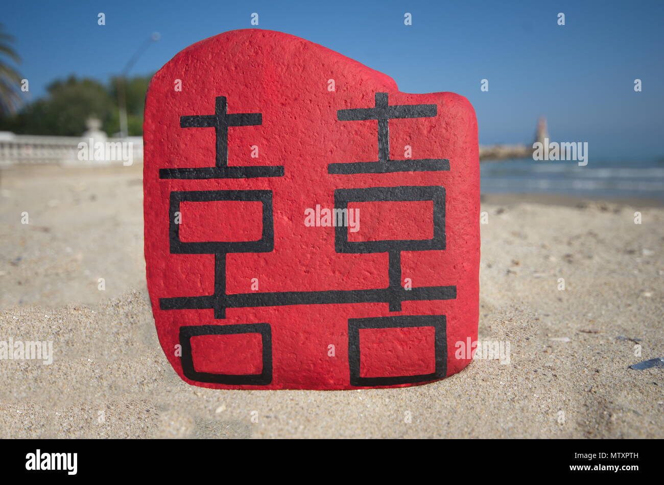 Double Happiness in chinesischer Sprache auf einem bemalten Steinen über den Strand Stockfoto