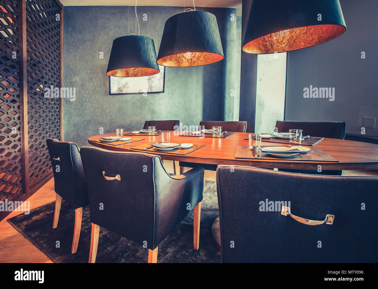 Stilvolle innen Einrichtung des mod-Restaurant. Das zeitgenössische Interieur die Holz- runder Tisch, bequeme Stühle und moderne Lampen. Exquisite Kombination der Royal Blau- und Orangetönen. Stockfoto