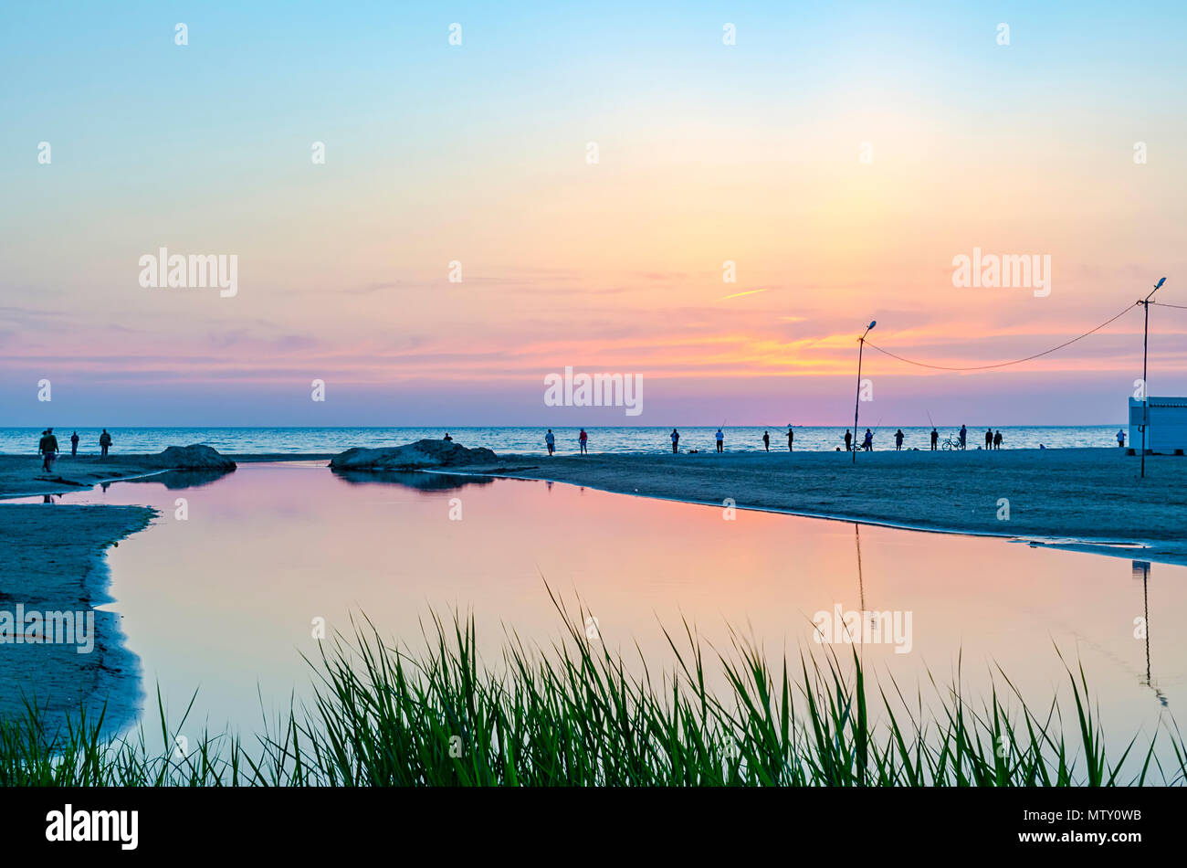 Touristen und Fischer sind am Schwarzen Meer und genießen Sie den schönen Sonnenuntergang. Stockfoto