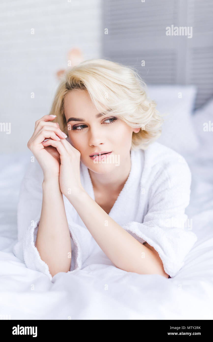 Nachdenklich attraktive blonde Frau im Bademantel weg schauen im Schlafzimmer Stockfoto