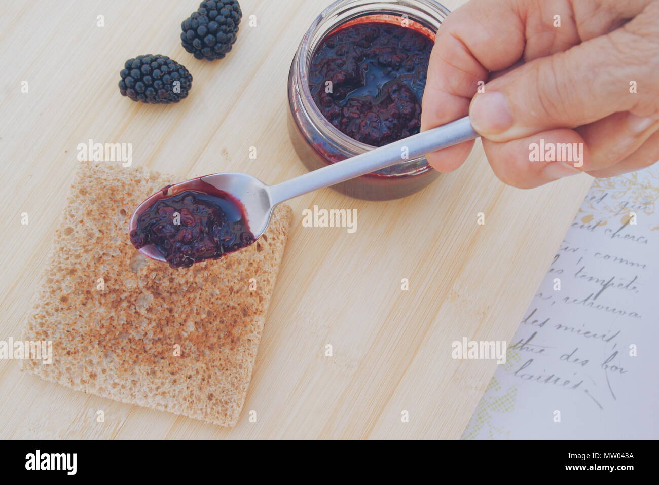 Frau putting Black jam auf Toast Stockfoto