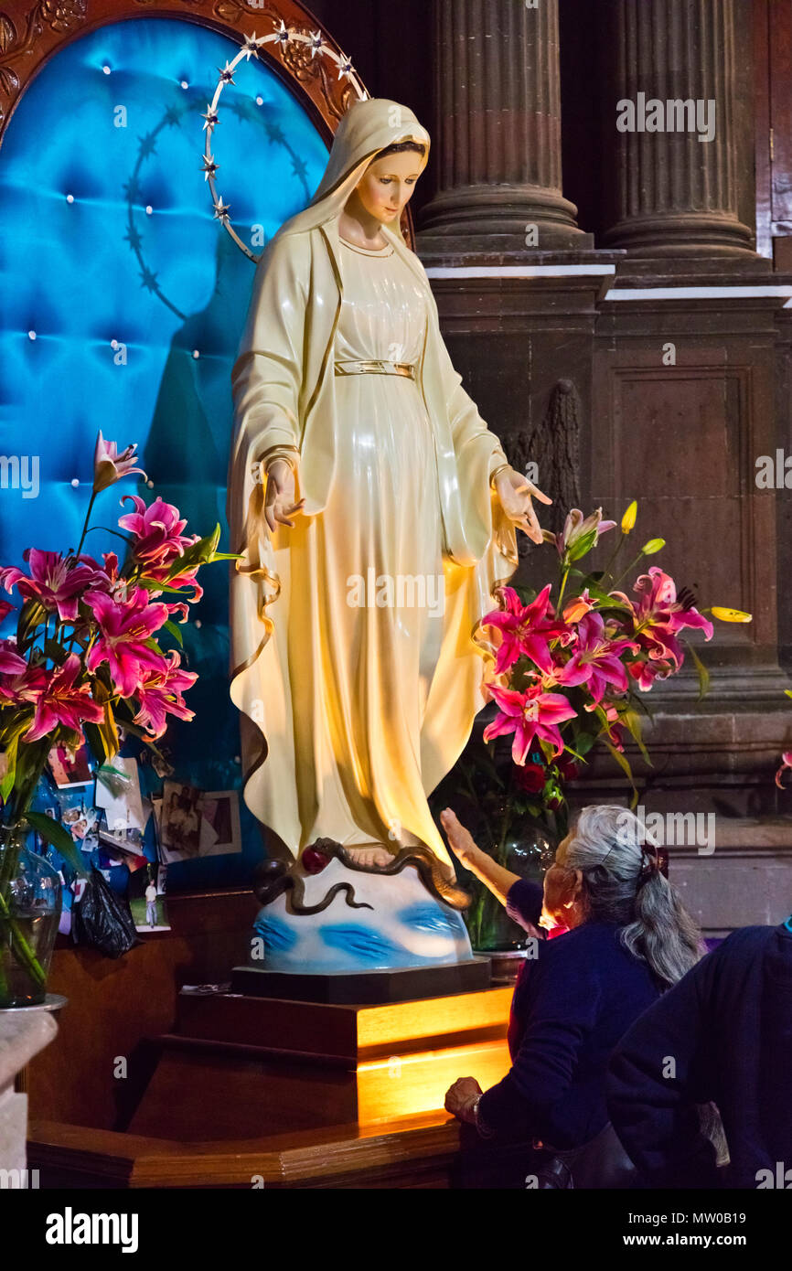 Eine katholische Frau verehrt, eine Statue der Jungfrau Maria am Karfreitag im Oratorium der Kirche Parroquia de SAN MIGUEL ACRCANGEL, SAN MIGUEL DE ALLE Stockfoto