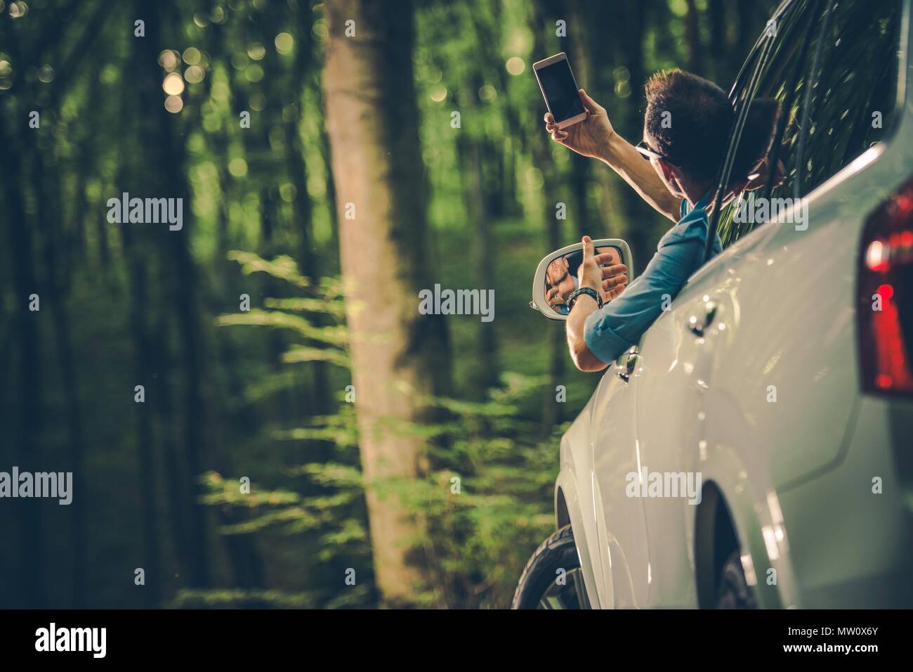 Kaukasischen Männern in seinem 30s auf der Suche nach Handy Signal aus seinem Auto. Stockfoto