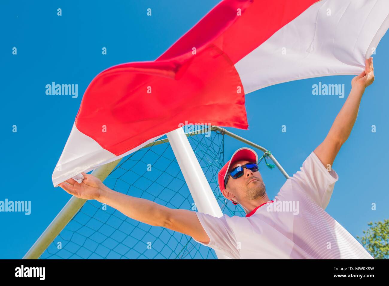 Kaukasische Fußballfan mit dem Polnischen roten und weißen Fahne in der Luft. Stockfoto