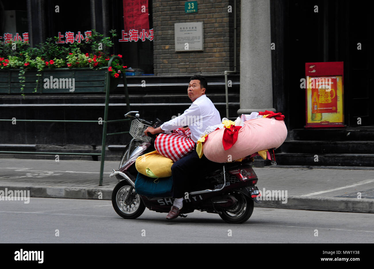 Candid Street Szene mit Mann auf einem Motorrad mit Wäscheservice, Shanghai, China geladen Stockfoto