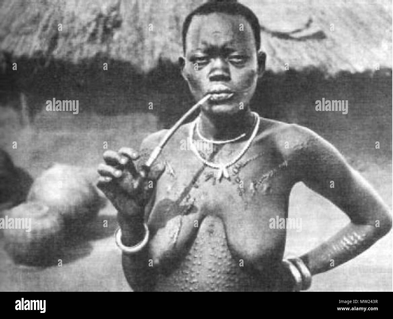 . Eine afrikanische Frau aus Shilluk Stamm Rauchen einer Pfeife (Foto in der Nähe von Malakal Stadt übernommen, South Sudan). Das Foto wahrscheinlich von Kazimierz Nowak (1897-1937) während seiner Reise durch Afrika - eine polnische Reisende, Korrespondent und Fotograf. Wahrscheinlich der erste Mensch an der Welt, die allein in Afrika von Norden nach Süden durchquert und von Süden nach Norden (von 1931 bis 1936; zu Fuß, mit dem Fahrrad und Kanu). . Ca. ca. 1931-36. Wahrscheinlich Kazimierz Nowak oder ein unbekanntes Thema 653 Frau rauchen Rohr Stockfoto