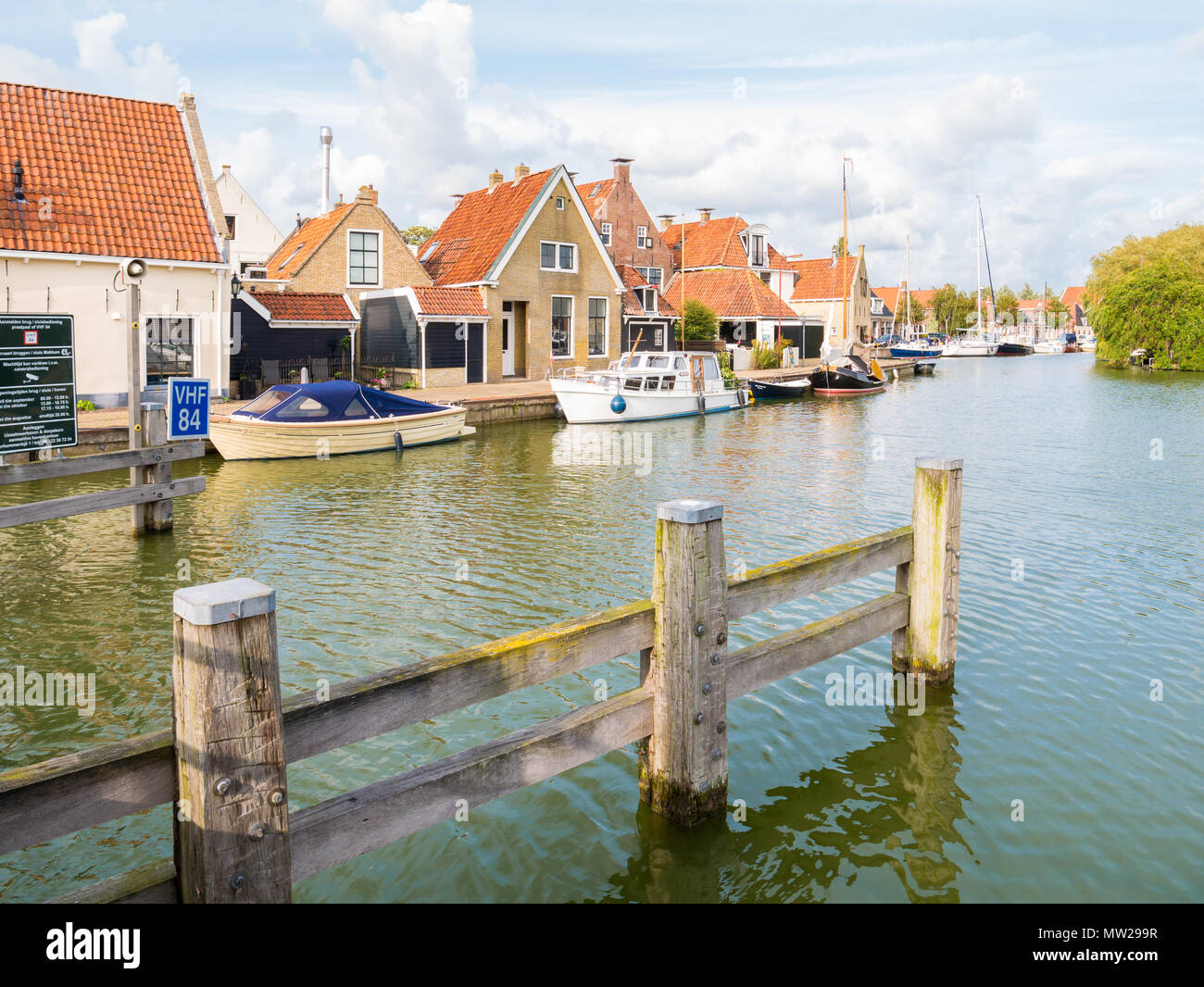 Hafen mit Booten und Kai mit historischen Häuser in der Altstadt von Makkum, Friesland, Niederlande Stockfoto