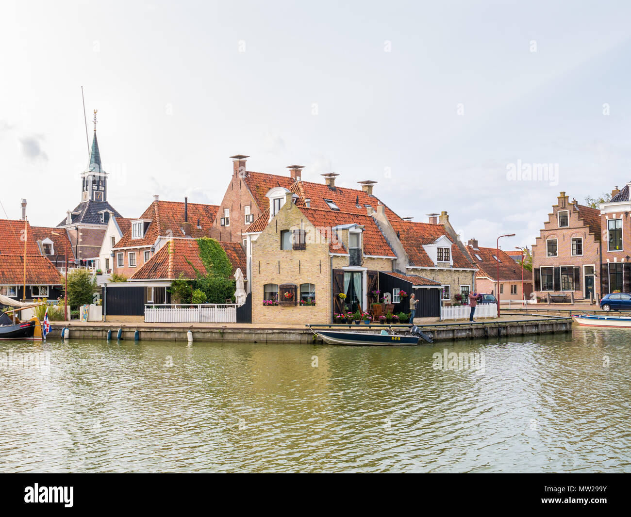 Hafen mit Booten und Kai mit historischen Häuser in der Altstadt von Makkum, Friesland, Niederlande Stockfoto