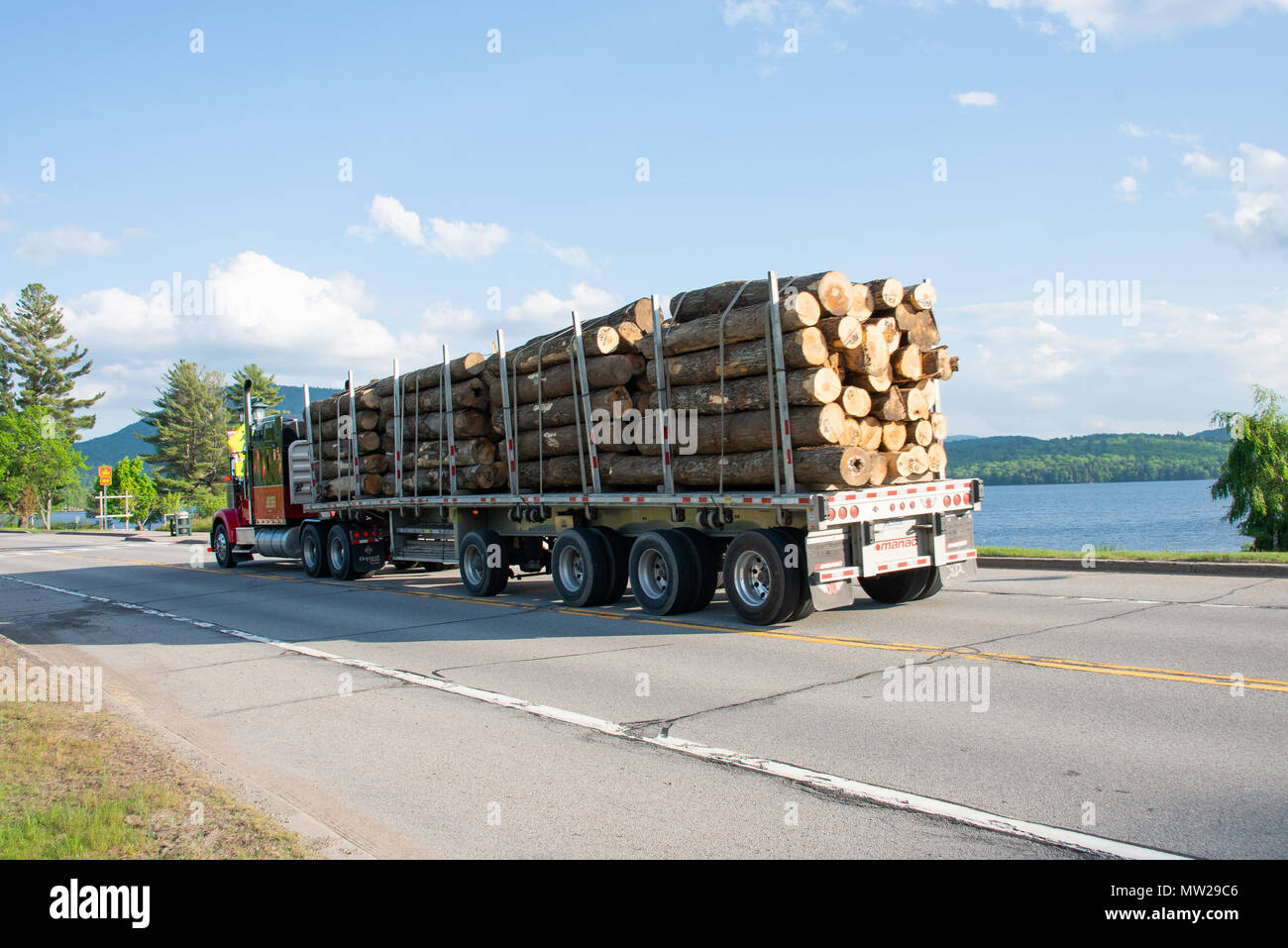 Schwer beladenen Lkw schleppen die Protokolle auf der Autobahn vorbei an Lake Pleasant log in den Adirondack Mountains, NY, USA Stockfoto