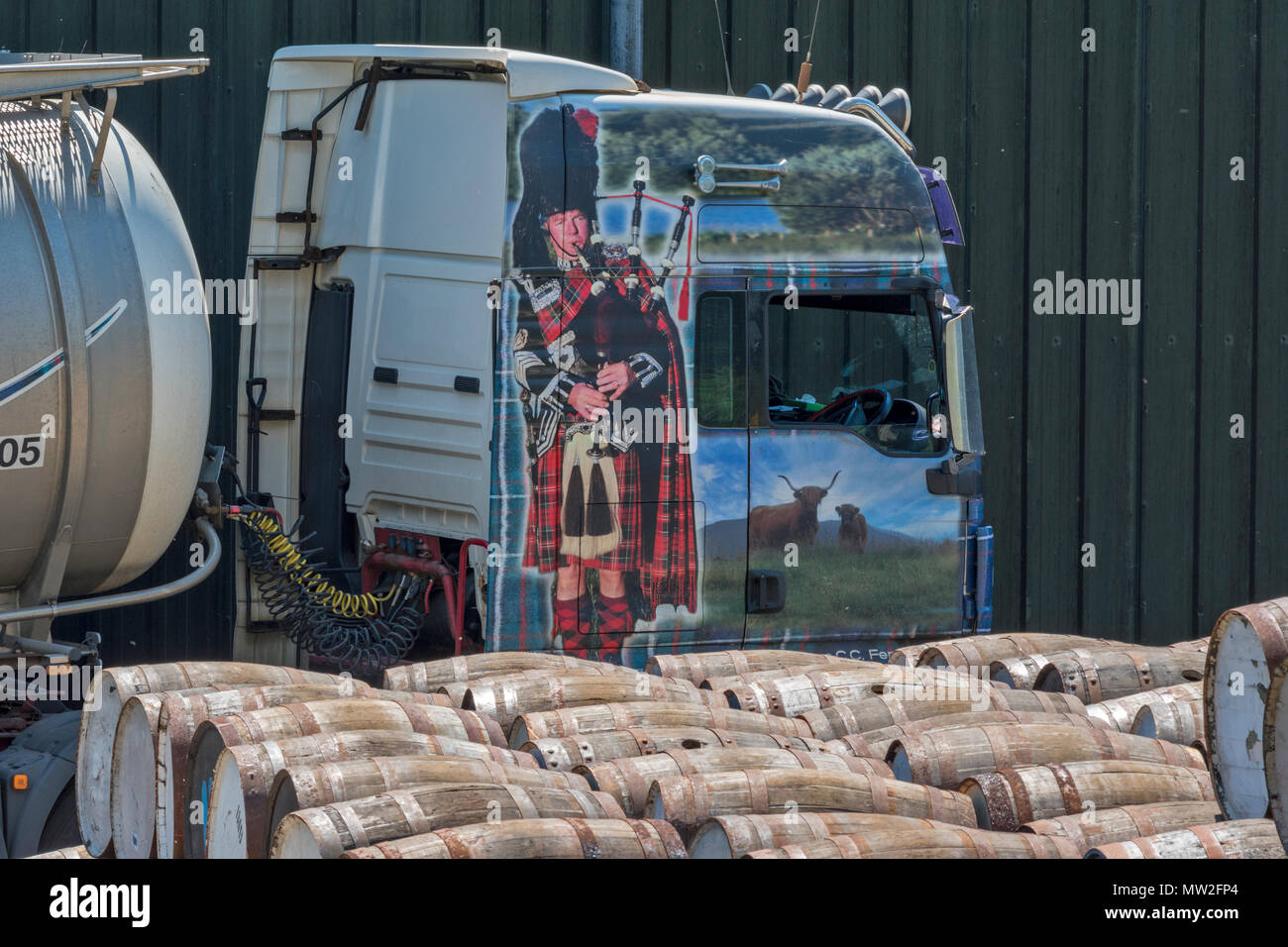 MALT WHISKY BARREL bei TAMDHU RIVER SPEY SCHOTTLAND MIT TRANSPORT LKW ODER FAHRZEUG BILD VON PIPER IN HIGHLAND DRESS GEMALT AUF DER KABINE Stockfoto