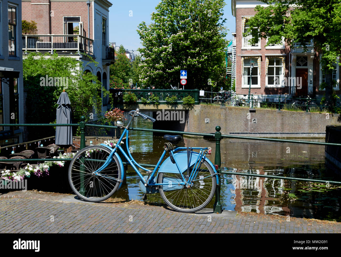 Blau Fahrrad auf Brücke über einem Kanal im Zentrum von Den Haag, Niederlande Stockfoto