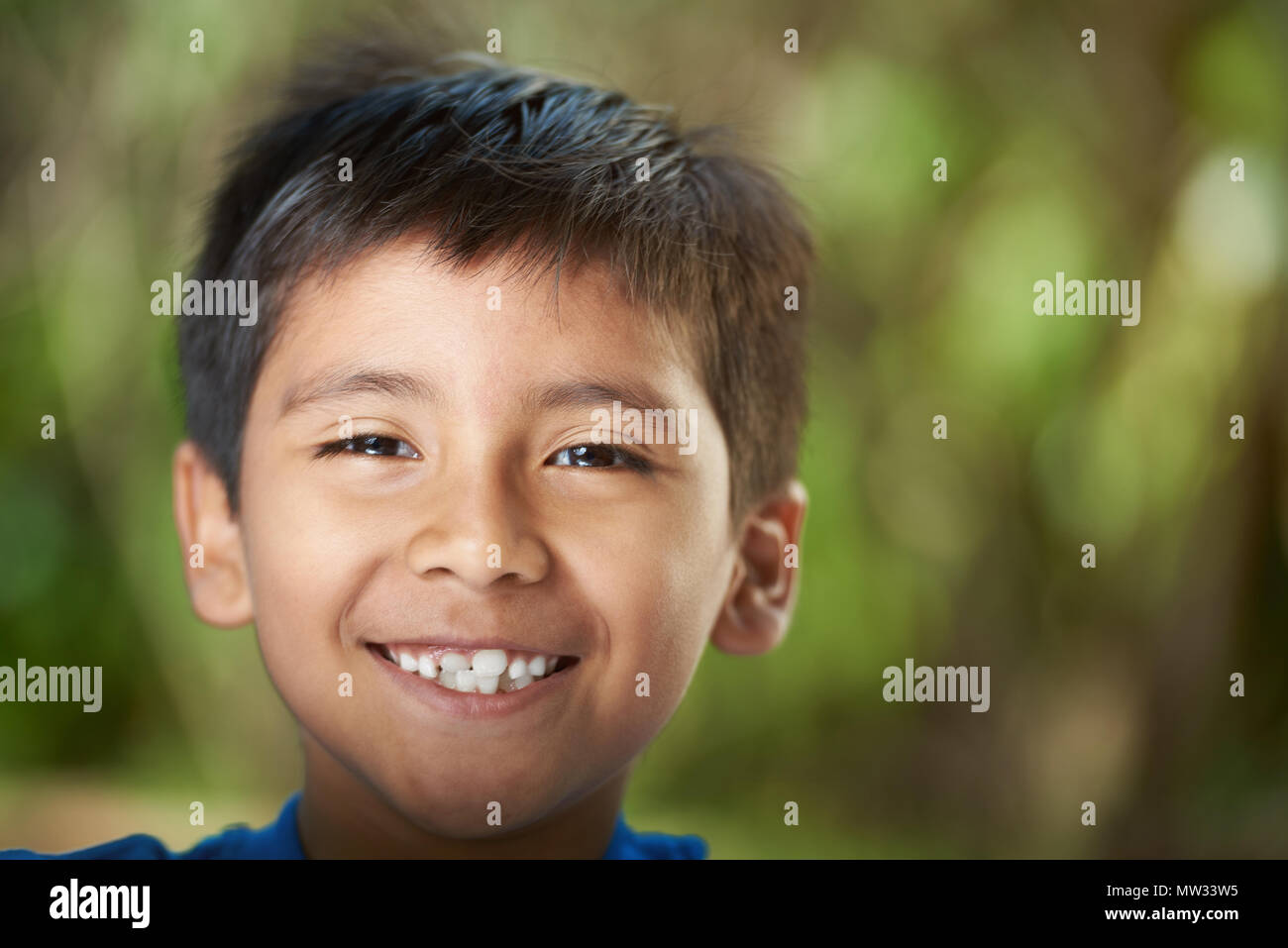 Lächelnd mit Zähnen Hispanic junge headshot auf unscharfen Sommer Hintergrund Stockfoto