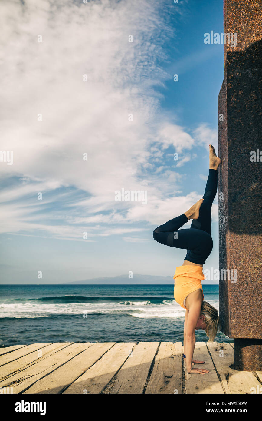 Frau meditieren yoga Pose, Blick aufs Meer, den Strand und die hölzernen Gehweg. Motivation und inspirierenden Sommer Meer Landschaft. Gesunder Lebensstil im Freien in Stockfoto