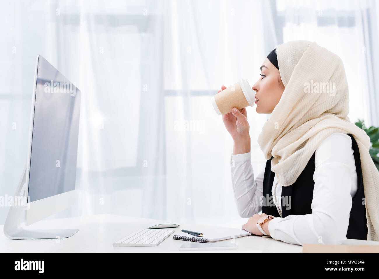 Seitenansicht des muslimischen Geschäftsfrau trinken Kaffee im Büro Stockfoto