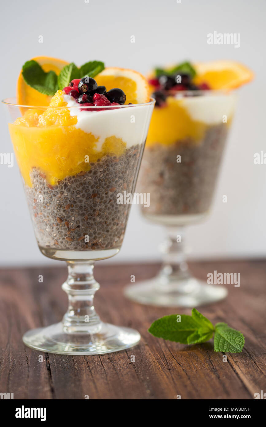 Chia Pudding mit Mango, Obst und Beeren dekoriert mit Minze auf einem Holzbrett vor einem weißen Hintergrund Stockfoto